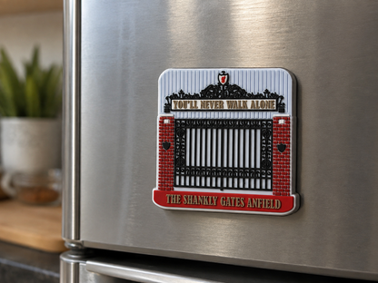 A rectangular refrigerator magnet featuring the Anfield gate design from 'You'll Never Walk Alone' by The Shanks, shown attached to a stainless steel fridge in a kitchen setting.